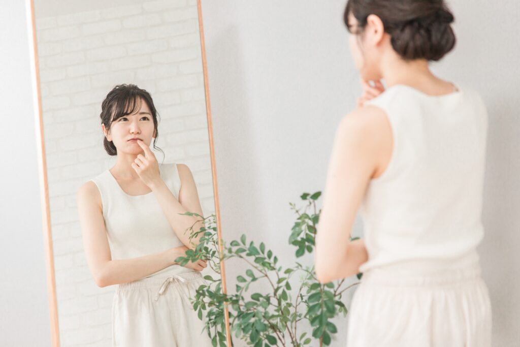 壁に立って自分の姿勢をチェックしている女性（猫背・反り腰の見分け）