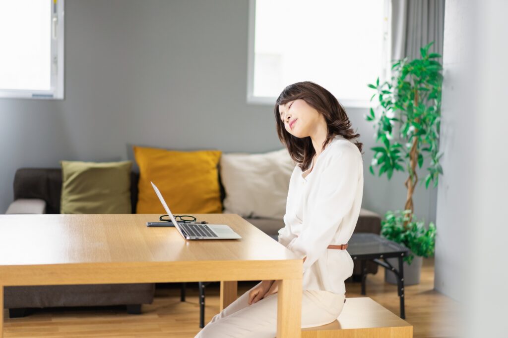 スマホ操作中に猫背姿勢になっている女性