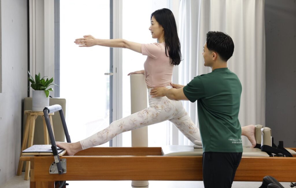 ピラティススタジオでトレーナーと1対1でレッスンを受ける様子
